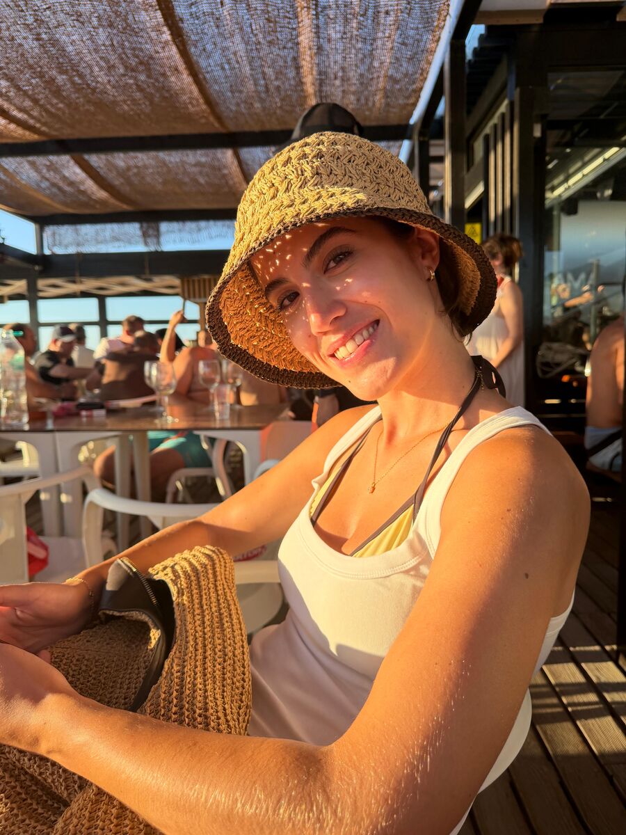 A Matilde a sorrir, com um chapéu de palha, ao pôr do sol